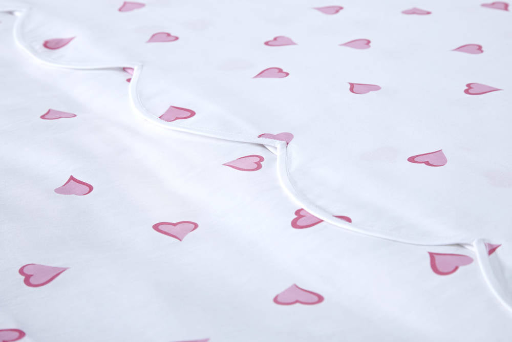 Close-up detail shot showing the pink heart design on sheets